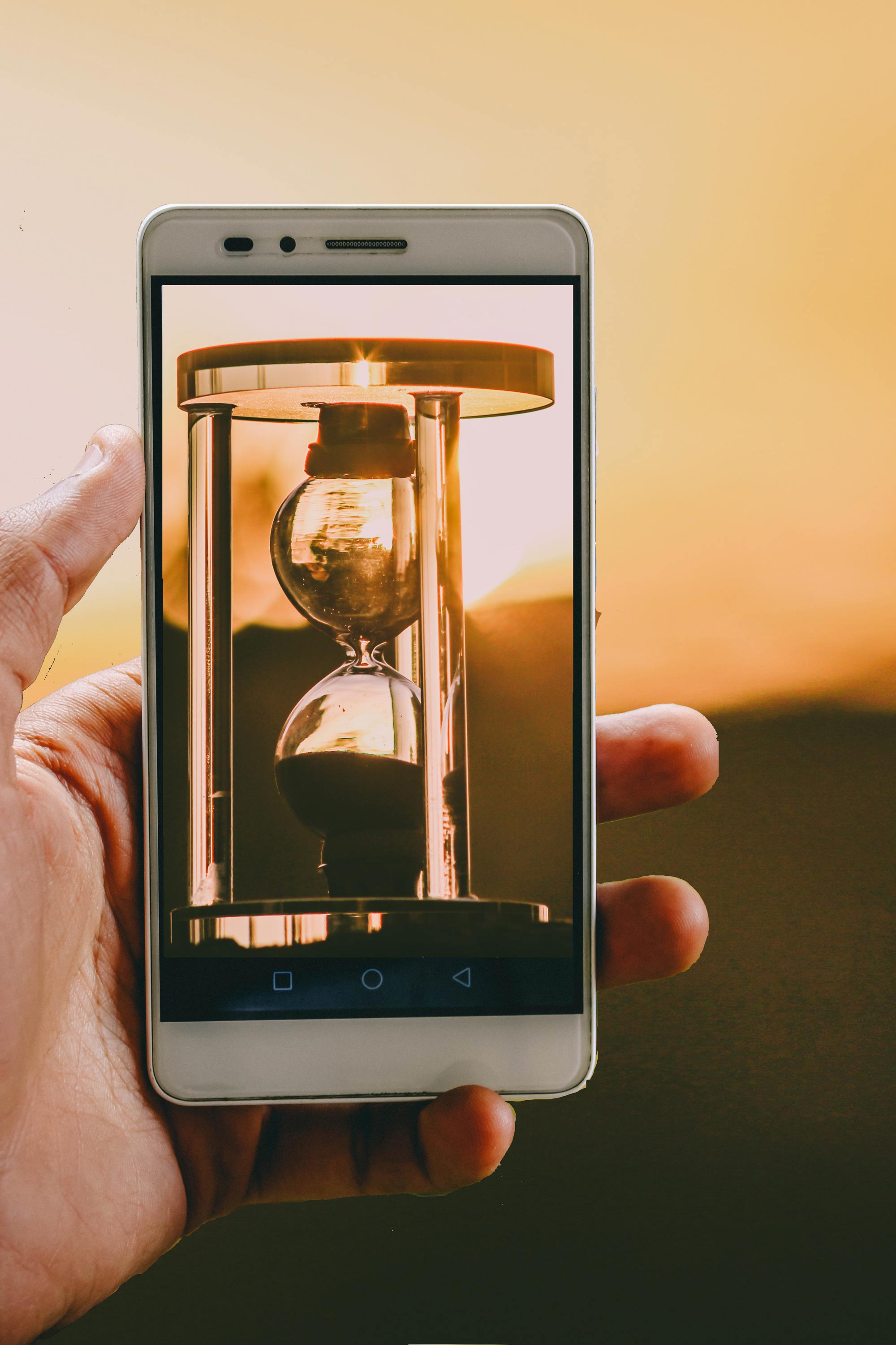 blurred-background-cellphone-cellular-telephone-1229456 A person holding up a cell phone with an image of a sand timer.